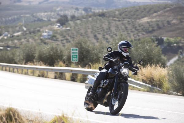 A Triumph Scrambler motorbike being ridden through a bend